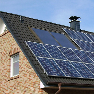 Photo of the top of a brick house with a black roof, covered in solar panels.